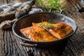 Salmon. Two juicy salmon steaks in roast pan with herb decoration on rustic oak table