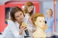 salon apprentice spraying chemical on mannequins wig Royalty Free Stock Photo