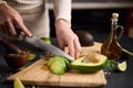 Salsa recipe - Woman Cutting slicing fresh green avocado fruit with knife on a wooden board at domestic kitchen Royalty Free Stock Photo