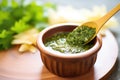 salsa verde in a ceramic dipper with a spoon