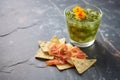 salsa verde with nachos on a stone surface