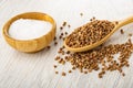 Salt cellar, scattered buckwheat, spoon with buckwheat on wooden table