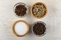 Salt, condiment in bamboo bowls, clove spice and peppercorn in bowls on wooden table. Top view