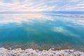 Salt crystals covering sand shore of Dead Sea, calm clear water surface near, typical morning scenery at Ein Bokek beach Royalty Free Stock Photo