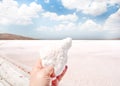 Salt crystals in hand against the background of a salty pink lake