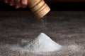 Salt falls from the grinder on a table full of salt. Hand holding salt grinder, heap of salt. Detail on grinder and salt pyramid