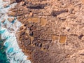 Salt farms in rocks of coast, ancient way of evaporation sea water by sun. Aerial top view.