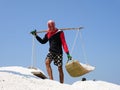 Salt field worker carrying salt with traditional shoulder pole