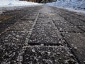 Salt grains on icy sidewalk surface in the winter