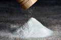 Salt grinder and pile of salt. Salt falls from the grinder on a table full of salt. Detail on grinder and pyramid of salt