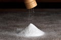 Salt grinder and pile of salt. Salt falls from the grinder on a table full of salt. Detail on grinder and pyramid of salt