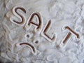 Salt inscription into a pile of white cooking salt on a wooden background. Sad face.