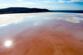 Salt lake of natural pink and orange color with salt accumulations near the shore. The sun is reflected on the water. Royalty Free Stock Photo