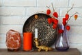 A salt lamp, a vase with dried plants, an aromatic orange candle and other decorative items