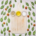 Salt, a mixture of peppers and olive oil on a white vintage cutting board laid out around spinach leaves and cherry tomatoes,,