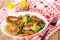 Salt and pepper, fried vegetable mix and cutlets in dish, fork on napkin on wooden table Royalty Free Stock Photo