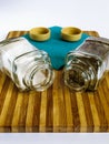 Salt and pepper in a glass shaker and pepper shaker stand on a cutting board