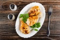 Salt and pepper, grilled chicken legs, leaves of parsley in dish, fork on table. Top view