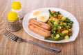 Salt, pepper shakers, plate with vegetable mix, boiled egg, fried sausages, fork on table Royalty Free Stock Photo