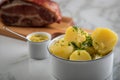 Salt potatoes with parsley, mustard and German Kassler neck pork meat on marble table