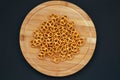 Salt pretzels on round wooden board on dark background,