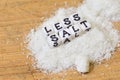 Less salt recommendation with salt on a wooden table.