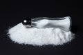 Salt shaker on a pile of salt on a black background. Excessive salt intake. Royalty Free Stock Photo