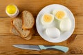 Salt, slices of bread, plate with whole eggs and halves of boiled egg, knife on wooden table. Top view Royalty Free Stock Photo