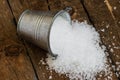 Salt spill out of the bucket tin on a wooden board