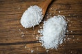 Salt in wooden spoon and heap of white salt on wood background
