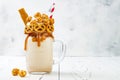 Salted caramel indulgent extreme milkshakes with brezel waffles, popcorn and whipped cream. Crazy freakshake food trend. Royalty Free Stock Photo