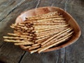 Salted chopsticks on a wooden plate. Deliciuse snack for a beer on the wooden table of old style. Food of breack time. Royalty Free Stock Photo