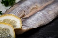 Salted Deboned Herring Fillets garnished with Yellow Onion, Lemon, Fresh Parsley and Peppercorns. Natural black stone . Royalty Free Stock Photo