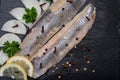 Salted Deboned Herring Fillets garnished with Yellow Onion, Lemon, Fresh Parsley and Peppercorns. Natural black stone . Royalty Free Stock Photo