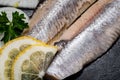 Salted Deboned Herring Fillets garnished with Yellow Onion, Lemon, Fresh Parsley and Peppercorns. Natural black stone . Royalty Free Stock Photo