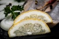 Salted Deboned Herring Fillets garnished with Yellow Onion, Lemon, Fresh Parsley and Peppercorns. Natural black stone . Royalty Free Stock Photo