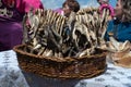 Salted, dried fish roach, strung on a wire, lies in a wicker willow basket standing on the table against women Royalty Free Stock Photo