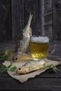salted, dried vobla fish with amber light beer on a dark wooden background with bread on the table Royalty Free Stock Photo