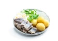 Salted herring with boiled potatoes and quial eggs on a white plate isolated on white