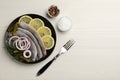 Salted herring fillets served with onion rings, pickles, dill and lemon on light beige wooden table, flat lay. Space for text