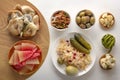 Salted mushrooms and watermelons in a wooden bowl on a background of fermented products on a white table.