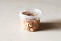 Salted peanuts in clear circle plastic container. Delicious and healthy snack for vegetarians, good with beer.