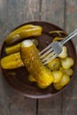 Salted pickled cucumbers on a fork in the foreground. in the background a plate of cucumbers Royalty Free Stock Photo