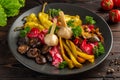 Salted and pickled vegetables on a black plate on a wooden background