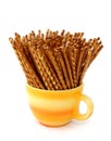 Salted sticks in yellow cup isolated on white Royalty Free Stock Photo