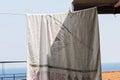 A beach towel hanging out in the sun on a terrace facing the sea. Vacation, attic.