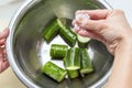 Salting fresh green sliced cucumber in the kitchen Royalty Free Stock Photo