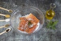 Salting salmon at home, fillet in a transparent bowl olive oil and various spices in wooden spoons Royalty Free Stock Photo