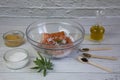 Salting salmon at home, fillet in a transparent bowl olive oil and various spices in wooden spoons Royalty Free Stock Photo