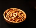 Salty beer snack pretzels with salt in a wooden bowl on a black background. Royalty Free Stock Photo